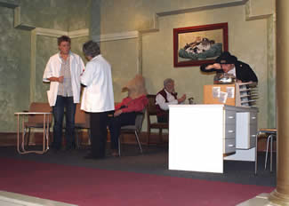 Overleg tussen verplegers Karin en Erwin, Frank eet vissoep